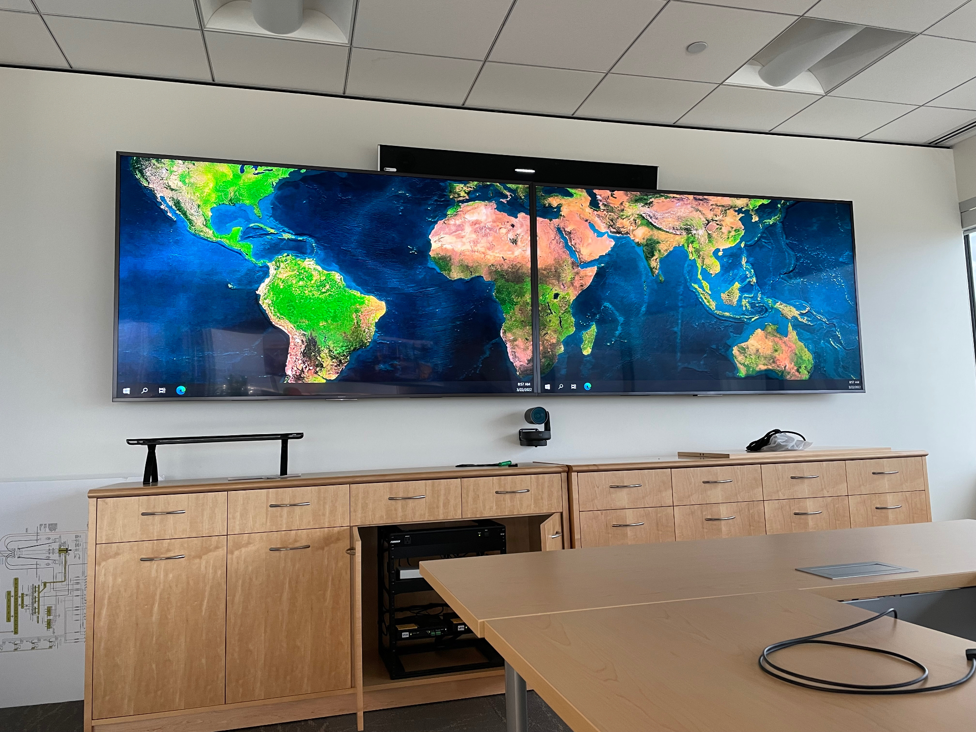 Dual large-format displays with PTZ camera, soundbar, and in-cabinet AV rack for hybrid meeting room